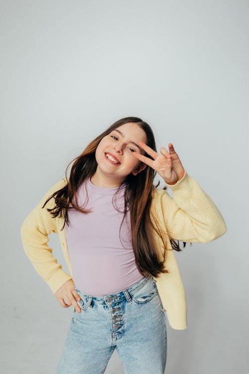 Free Girl Wearing a Sweater Doing a Peace Sign Pose Stock Photo