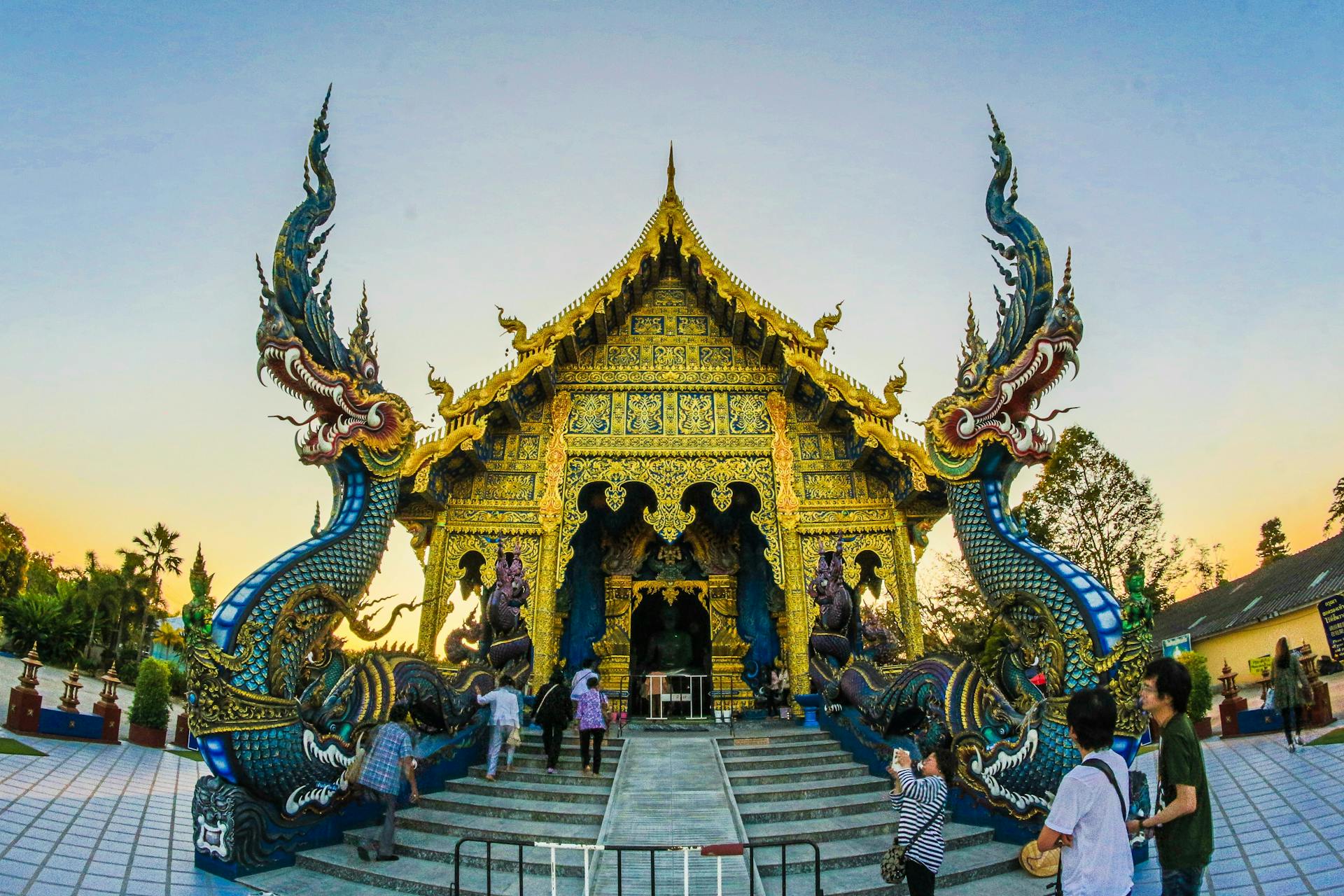 Stunning Thai temple adorned with ornate dragon sculptures at sunset, a blend of art and spirituality.