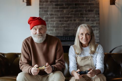 Free Happy elderly couple having fun playing video games together at home. Stock Photo