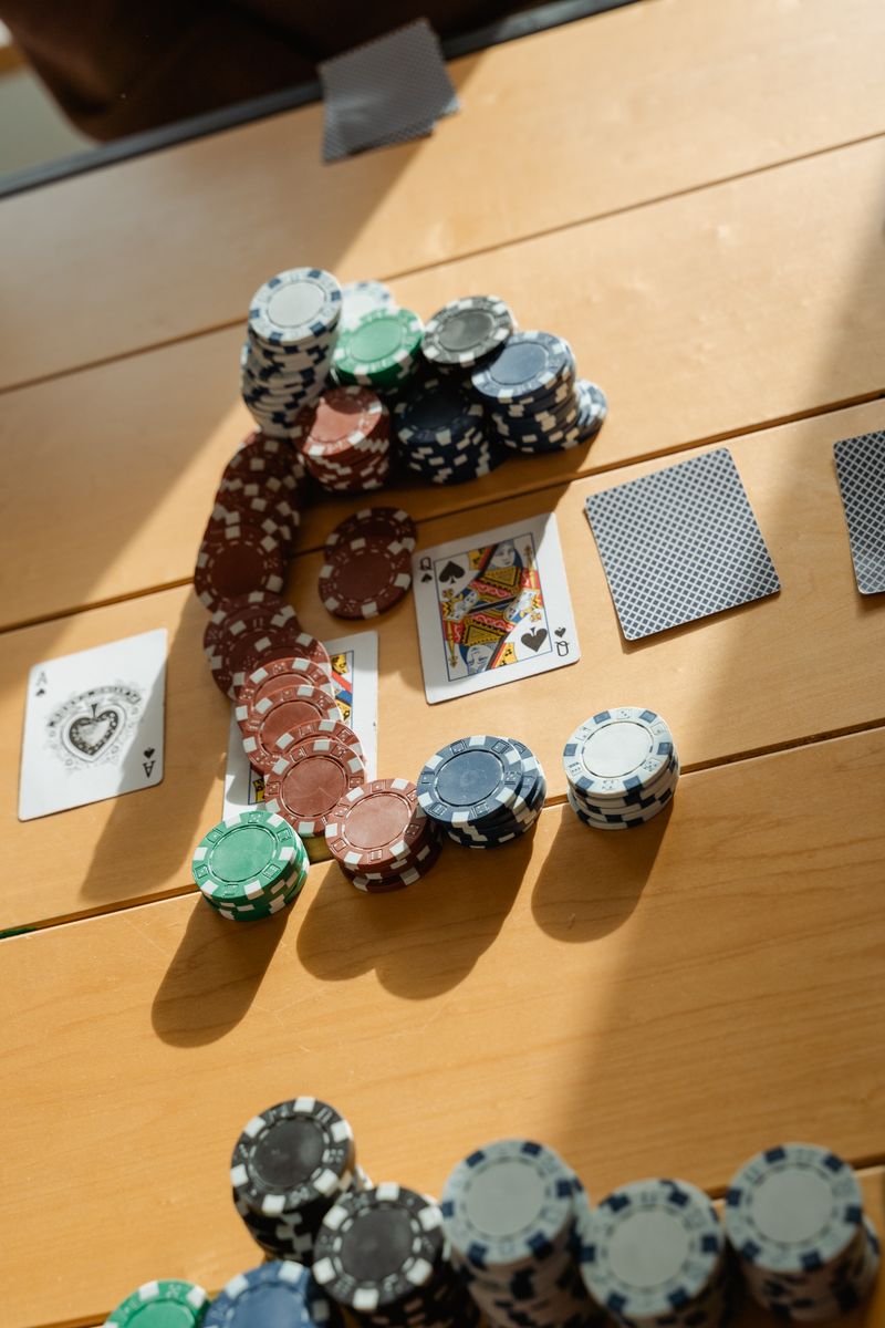 Playing cards and poker chips arranged on a wooden table in natural light