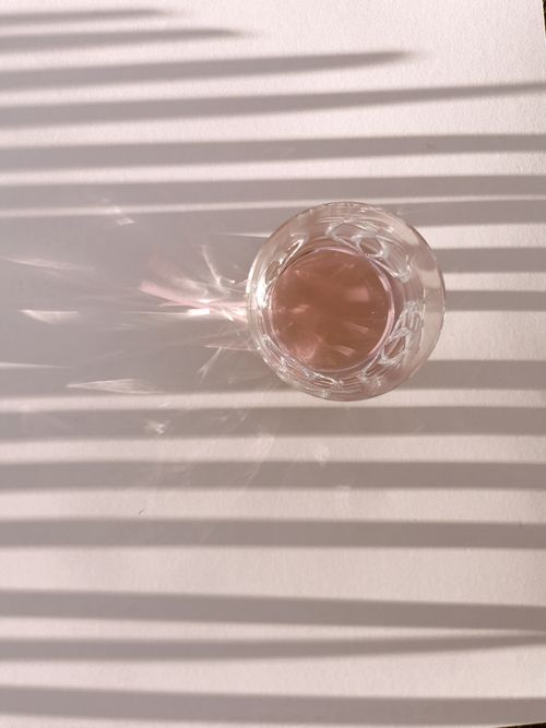 Free Top view glass cup of pink wine placed on shade of exotic palm leaf Stock Photo