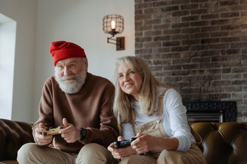 Free Elderly couple joyfully playing video games together in a cozy living room. Stock Photo
