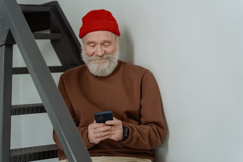 Free Man in Brown Sweater Holding a Smartphone Stock Photo