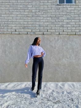 Elegant woman posing in winter outfit against a brick wall in Canada.