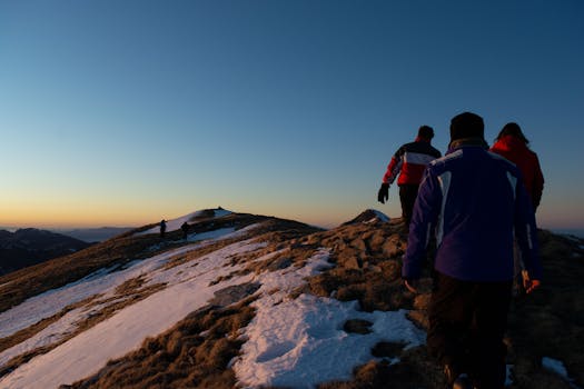 Group of hikers exploring snowy mountain terrain at sunset in Italy.