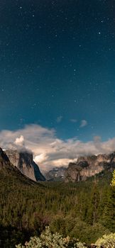 A panoramic view of Yosemite Valley under a star-filled night sky.