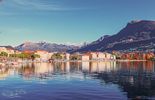 Picturesque coastal town with mountains reflecting in the tranquil lake waters. by Robert  Stokoe