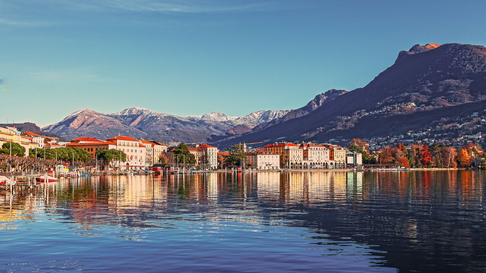Picturesque coastal town with mountains reflecting in the tranquil lake waters.
