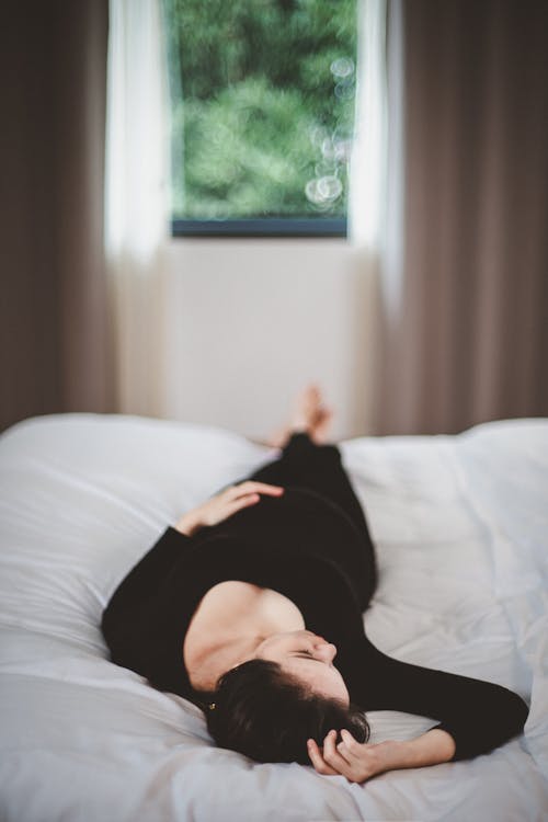 Free A Woman in Black Long Sleeves Lying on the Bed Stock Photo