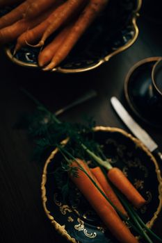 Elegant display of fresh carrots on a vintage ceramic platter with intricate gold designs.