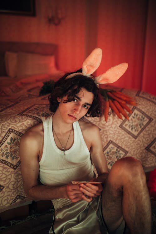 A Young Boy in White Tank Top Sitting Near the Bed