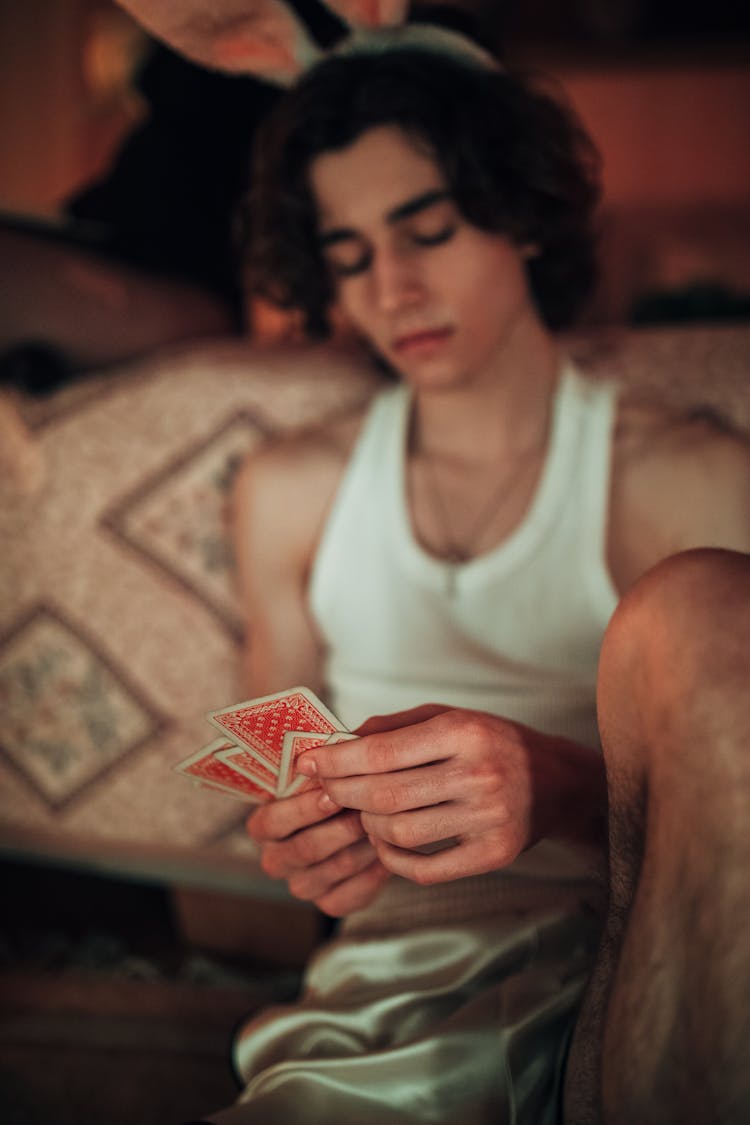 A Young Boy In White Tank Top Holding A Playing Cards