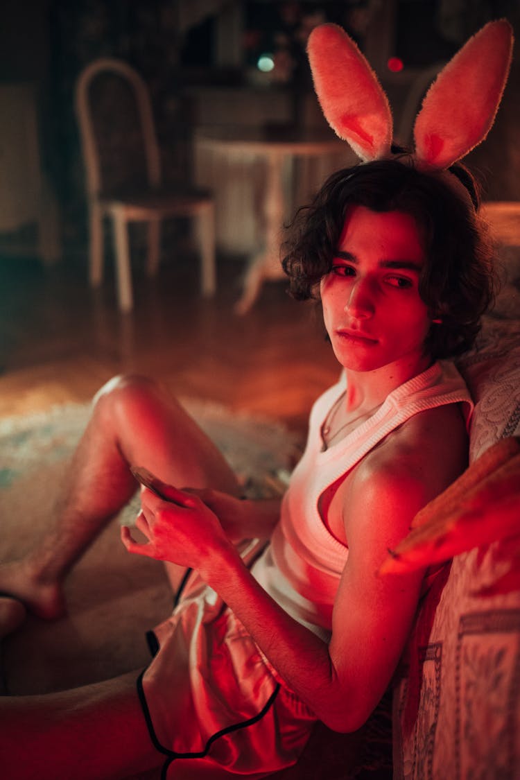 A Boy In White Tank Top Sitting Near The Bed