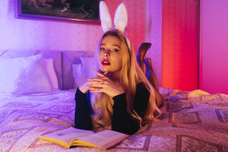 A Woman Wearing A Bunny Ear Headband Lying Down On The Bed