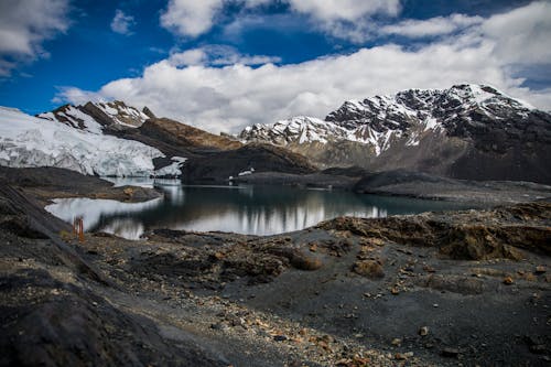 Lake near Snow-Covered Mountains under the Cloudy Blue Sky