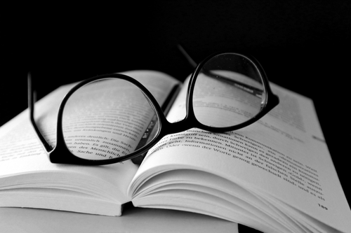 Free Open book with glasses on top, captured in dramatic black and white. Stock Photo