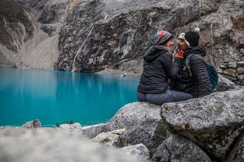 A Couple Sitting on a Rock Near a Lake