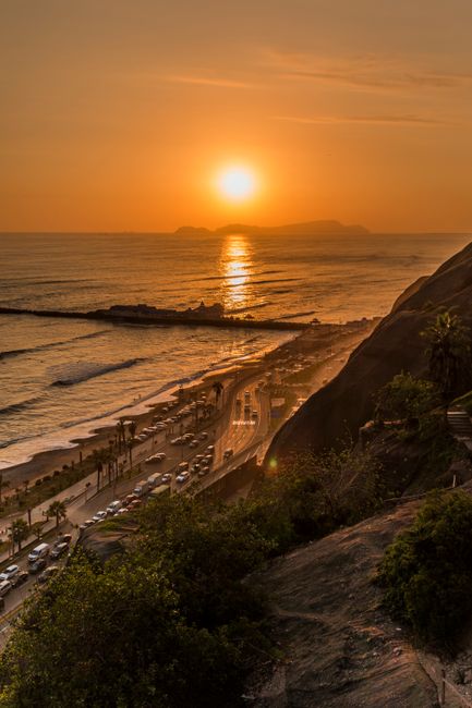 Stunning sunset view of Lima's coast with vibrant ocean and moving traffic.