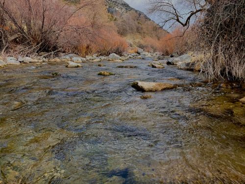 Free Serene river flowing through a barren winter landscape with rocky terrain. Stock Photo
