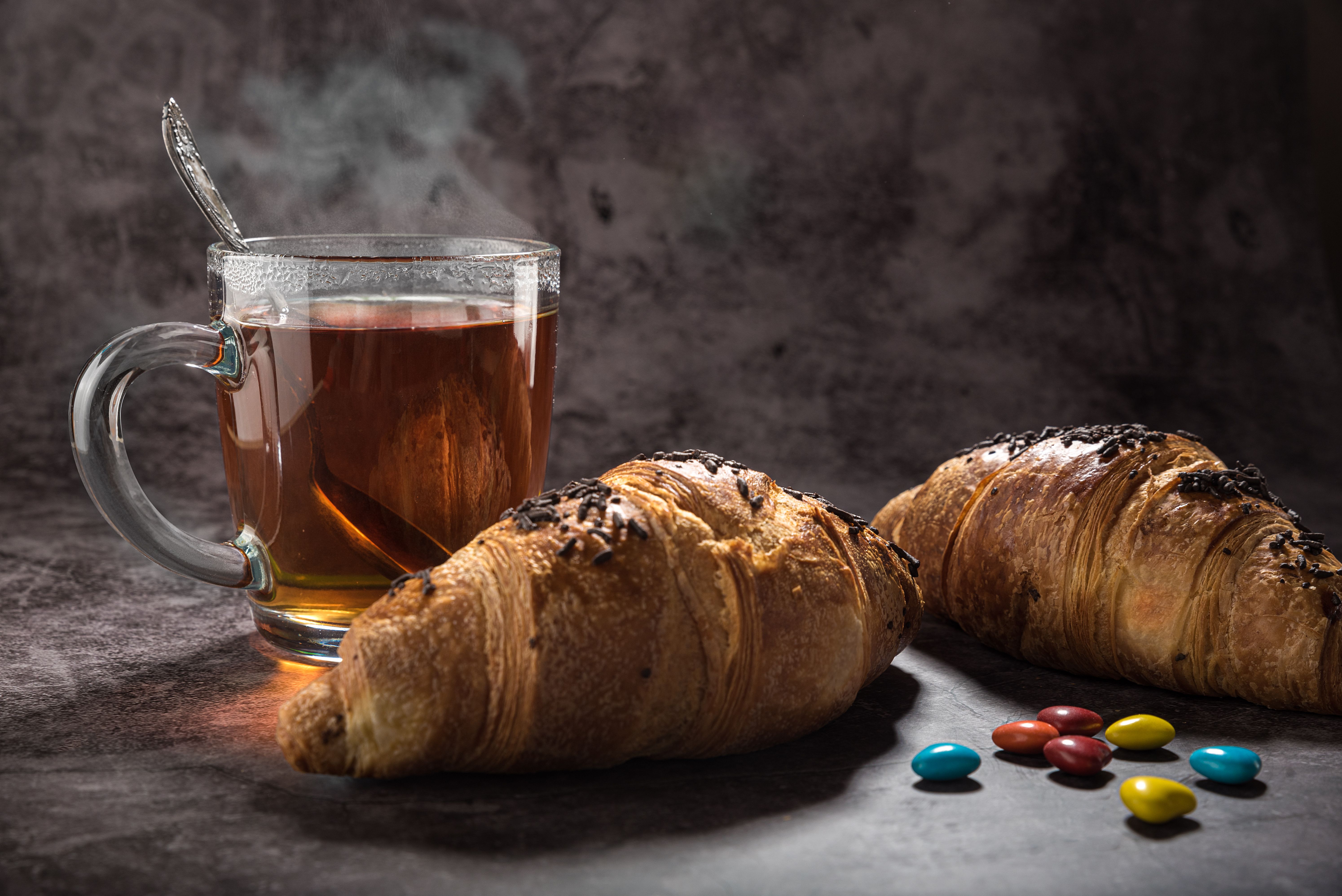 Steaming cup of fennel tea next to a plate of food on a wooden table.