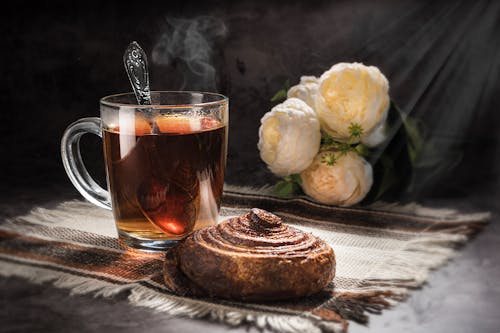 Free A Glass of Hot Tea and a Cinnamon Bread on a Table Mat Stock Photo