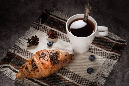 Free Close-up of a fresh croissant and hot coffee on a rustic table setting. Stock Photo
