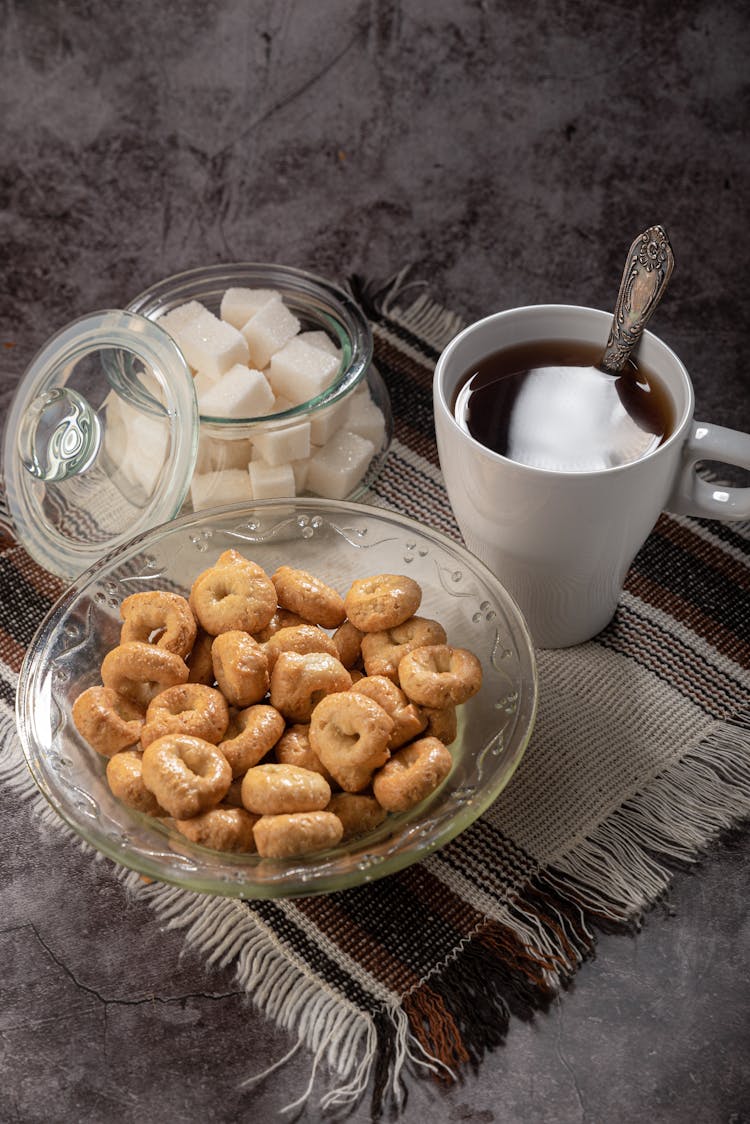 A Cup Of Tea And Sweet Snacks In Glass Containers 