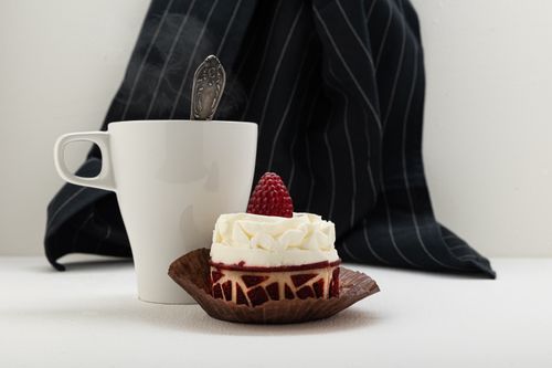 Free A delicious raspberry cake beside a steaming coffee cup on a white table. Stock Photo