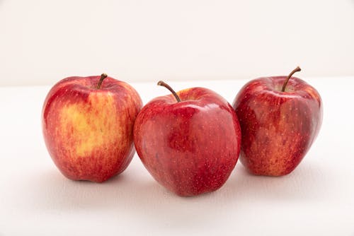 Three Red Apples on White Surface