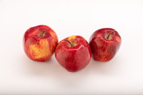 Free Three vibrant red apples resting on a clean white surface, showcasing freshness and health. Stock Photo