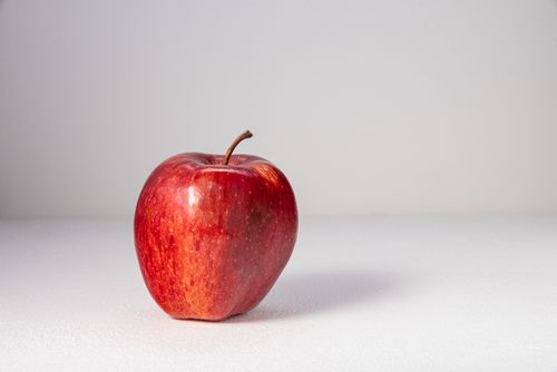 Free Close-up of a fresh red apple on a white surface, highlighting its glossy skin. Stock Photo