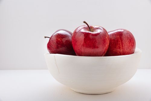 Free Close-up of vibrant red apples in a white ceramic bowl on a white background, emphasizing health and simplicity. Stock Photo
