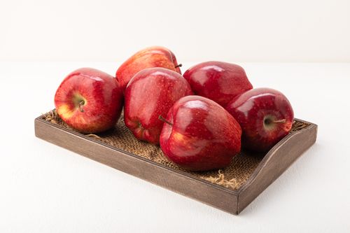 Free Juicy red apples displayed on a rustic tray, perfect for healthy eating concepts. Stock Photo