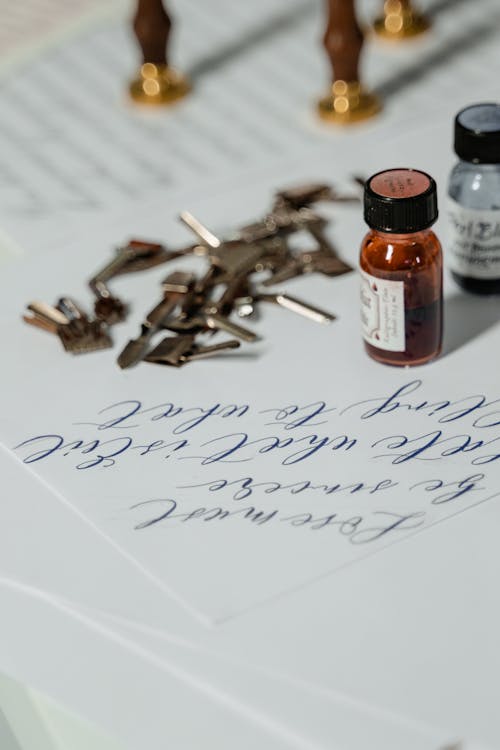 Ink Bottles and Calligraphy Tools on White Paper