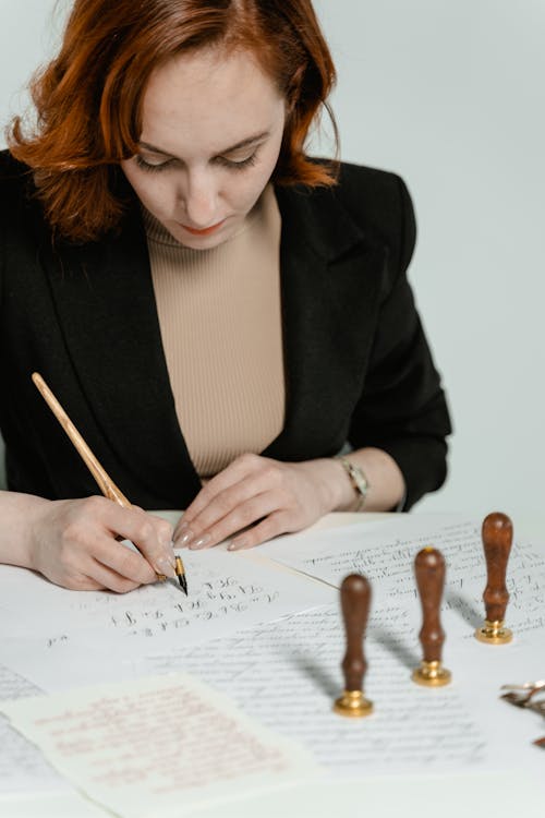 Woman in Black Blazer Writing on White Paper