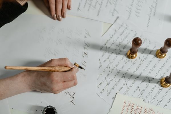 Hand lettering with a wooden pen beside wax seals — photo by MART PRODUCTION on Pexels
