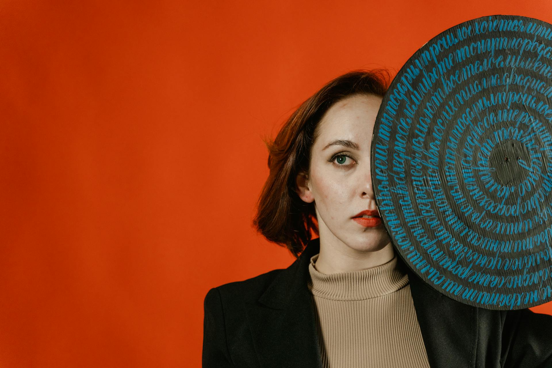 Woman in Black Blazer Covering Face With Round Object