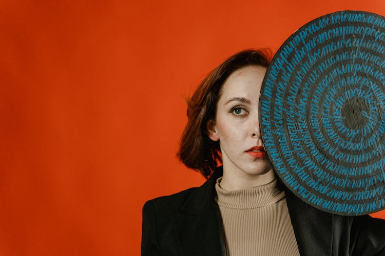 Woman In Black Blazer Covering Face With Round Object