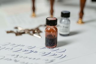Student project: ink bottles beside a written page — MART PRODUCTION on Pexels