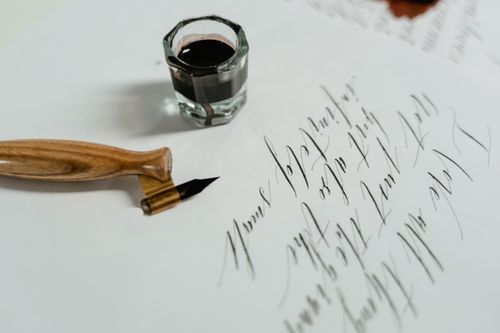 Free Close-up of calligraphy writing with a fountain pen and ink, showcasing artistic handwriting on paper. Stock Photo