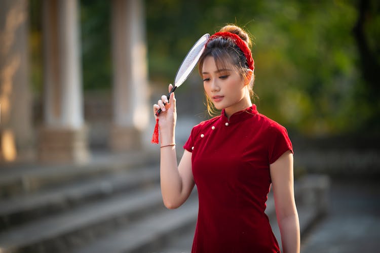 Asian Lady Touching Head With Fan Near Porch