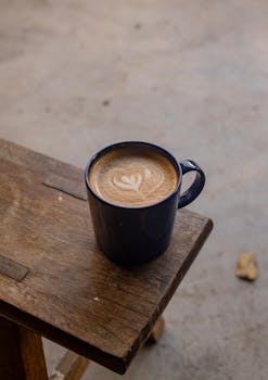 A beautifully crafted cappuccino with latte art served on a rustic wooden table.