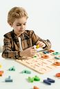 Boy in Black and White Plaid Button Up Shirt Playing With White and Yellow Game Board