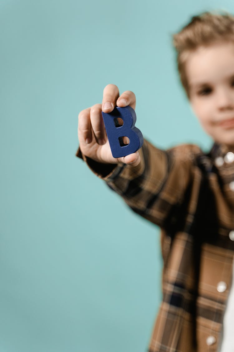 Boy Holding A Blue Carved Wooden Letter 