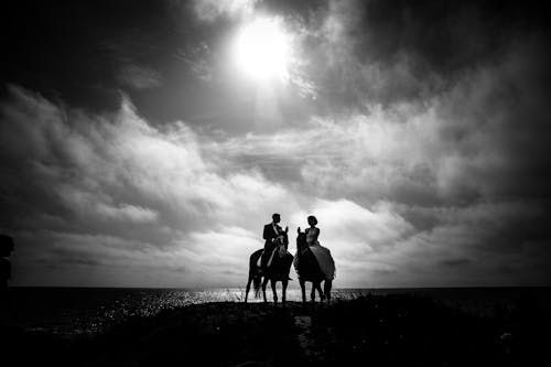 Graustufen Fotografie Des Paares, Das Auf Pferd Mit Gewässern Und Himmel Als Hintergrund Reitet