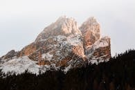 黎明时分，白雪覆盖的山峰被茂密的森林环绕，景色壮丽