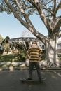 Man in Green and White Striped Polo Shirt Standing Under Tree