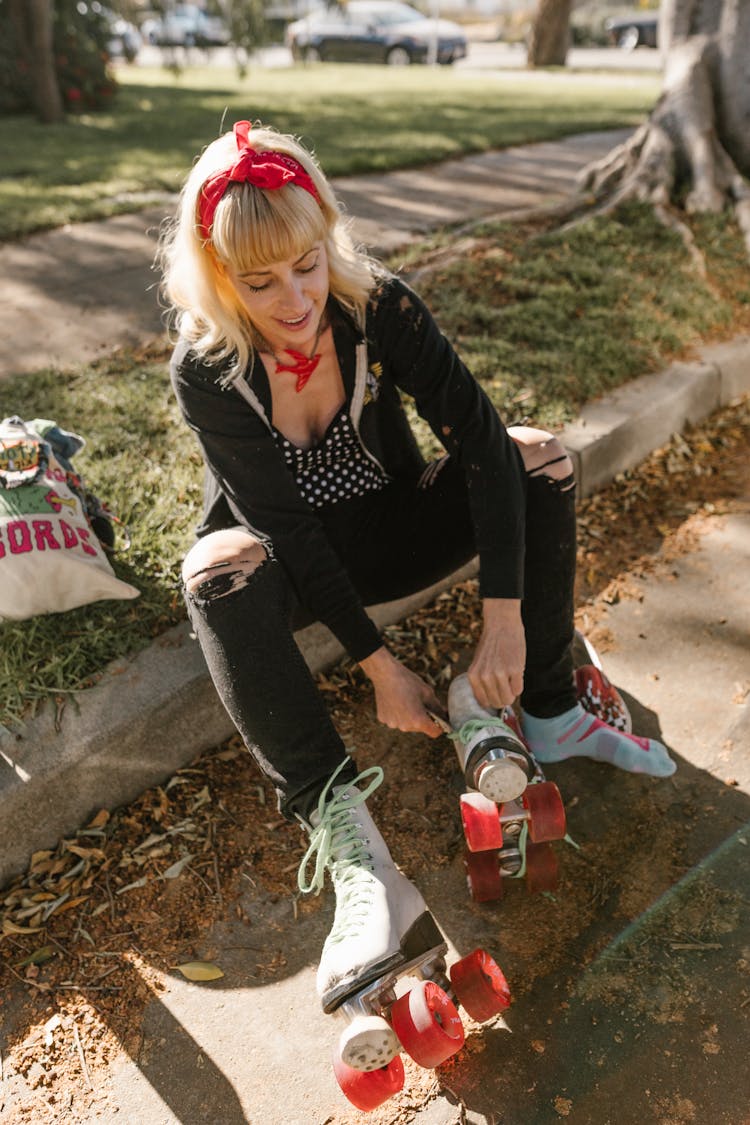 A Woman Sitting On The Gutter While Wearing Her Roller Skates