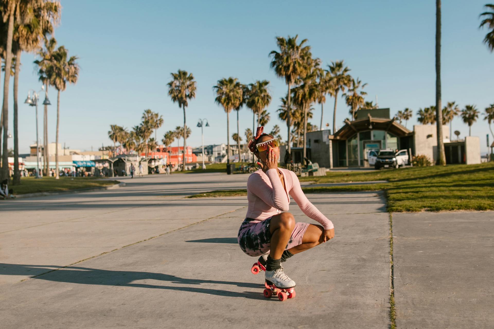 Woman in stylish outfit roller skating at Venice Beach, enjoying sunny day outdoors.