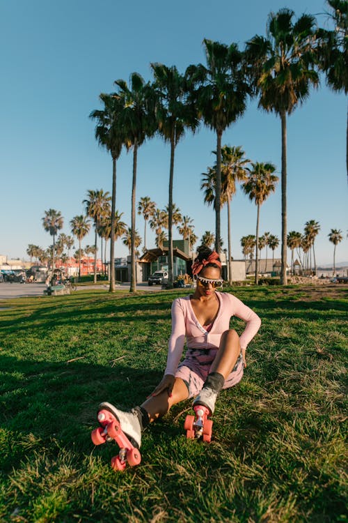 Woman in Pink Long Sleeve Shirt Sitting on Green Grass Field